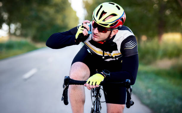 Sports and asthma. Cyclist using asthma inhaler while riding a bicycle. Sport and recreation concept stock photo