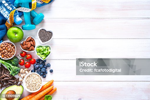 istock Sports and healthy food concept: fruits, vegetables, nuts, dumbbels and tape measure. Copy space 1273909829