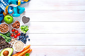 istock Sports and healthy food concept: fruits, vegetables, nuts, dumbbels and tape measure. Copy space 1273909829