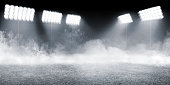 Sports arena with concrete floor with smokes and spotlights against dark background