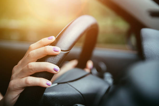 Sports car steering wheel, hands of a young girl with purple nail polish stock photo