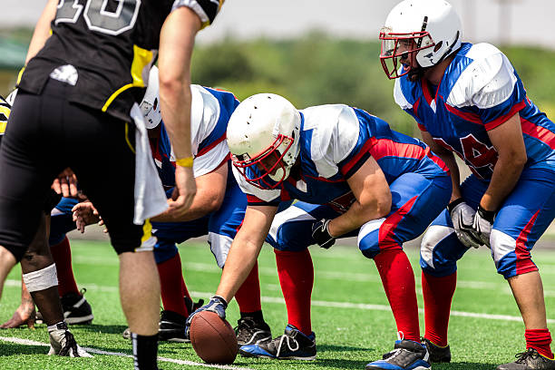 Sports: Football teams prepare for a play.  Line of scrimmage. Center prepares to hike the football to the quarterback. Line of scrimmage.  high school sports stock pictures, royalty-free photos & images