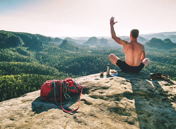 スポーツマンは岩の山頂で朝食をとる。スポーツとモチベーション - 登山　夏 ストックフォトと画像