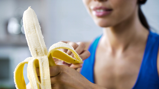 Sports woman peeling sweet banana for snack, hungry after active workout in gym, stock footage
