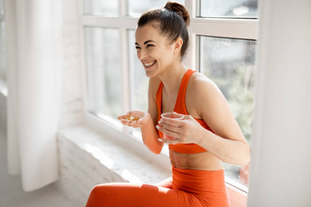 Sports woman takes supplements or vitamins at gym stock photo