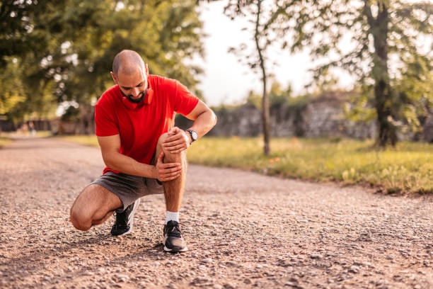 Sportsman hurting his knee during running stock photo
