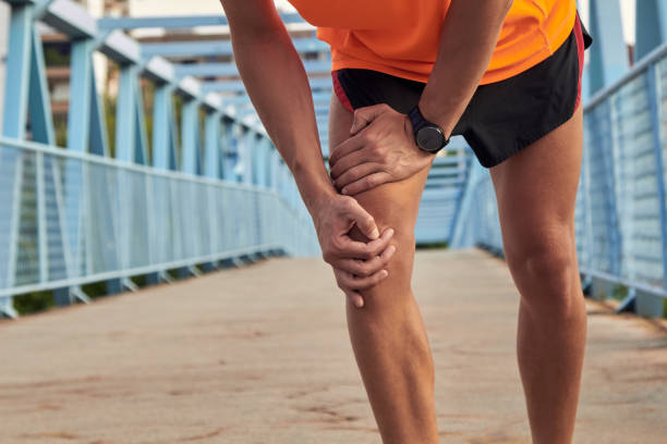 Sportsman with leg injury during jogging and exercising in urban environment. stock photo