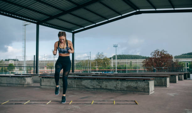 Sportswoman jumping on an agility ladder stock photo