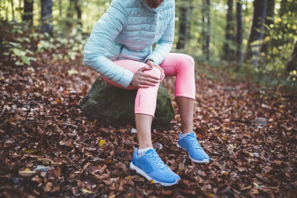 Sportswoman with sprained knee Woman in the park holding painful knee after sports injury knee stock pictures, royalty-free photos & images