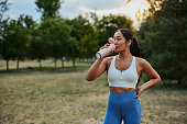 istock Sporty young woman drinking water while exercising at the park 1342807655