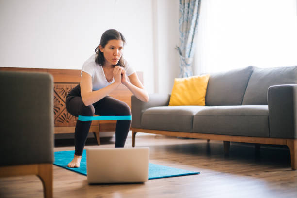 Sporty young woman exercising at home with resistance band Sporty young woman exercising at home with resistance band resistance band stock pictures, royalty-free photos & images