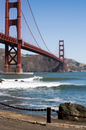 Surfer enjoying the ocean under the beautiful Golden Gate Bridge.