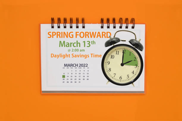 Spring Forward March 2022 Alarm clock and Spring Forward Calendar on orange background daylight saving time stock pictures, royalty-free photos & images