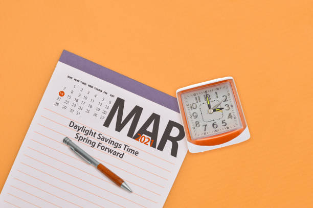 Spring Forward March 2021 Calendar Spring Forward Daylight Savings Time Notepad and clock on orange background daylight savings 2021 stock pictures, royalty-free photos & images