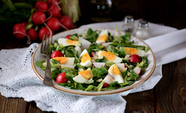 Spring green salad from organic radish, wild garlic with boiled eggs, olive oil and parmesan. stock photo