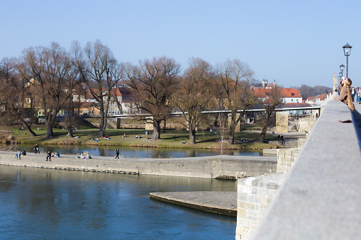 Regensburg, Germany - February, 25th 2021: People enjoying spring by the river Danube in Regensburg city center