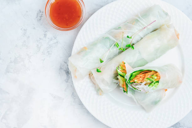 Spring roll with vegetables and shrimp. On a light gray concrete, white plate with an Asian snack. Photo with copy space. stock photo