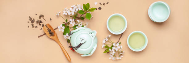 Spring tea ceremony. Herbal tea in cups, teapot and branches of blossoming cherries. Top view. Flat lay stock photo