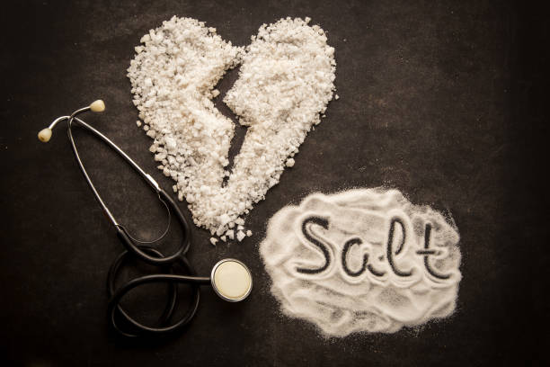 Sprinkled salt on dark background with broken heart shape made from salt. stock photo