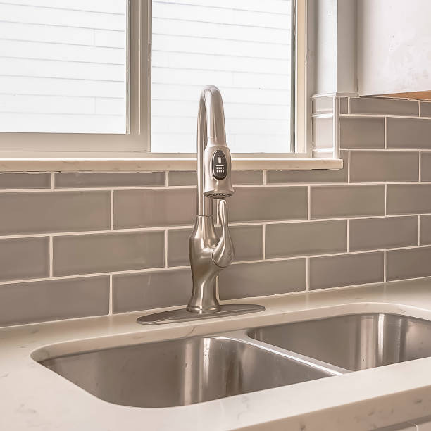 Square frame Undermount double bowl sink and faucet on the gleaming white kitchen countertop stock photo