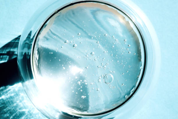 Squeezed cosmetic clear cream-gel texture. Close up photo of transparent aloe vera gel with bubbles in a glass bowl on blue background. Skincare, healthy product stock photo