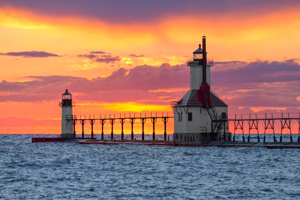 St. Joseph Sunset The St. Joseph, Michigan North Pier Inner and Outer Lighthouse shine their lights backed by a dramatic and colorful sunset on Lake Michigan. north pier stock pictures, royalty-free photos & images