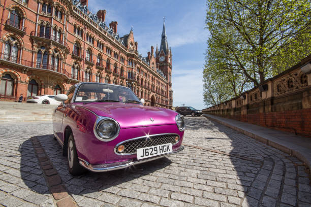 St Pancras Renaissance Hotel, London St Pancras, London, UK - May 5, 2016.  A vintage or classic, purple car parked outside The St Pancras Renaissance Hotel in Kings Cross London, UK which is a popular five star hotel and tourist landmark with ornate, Gothic architecture and elaborate, curved facade. purple classic car stock pictures, royalty-free photos & images