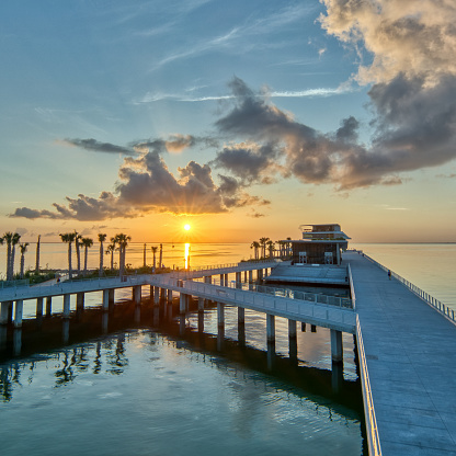 The St Pete Pier in St. Petersburg, Florida as the sun is rising over a calm Tampa Bay