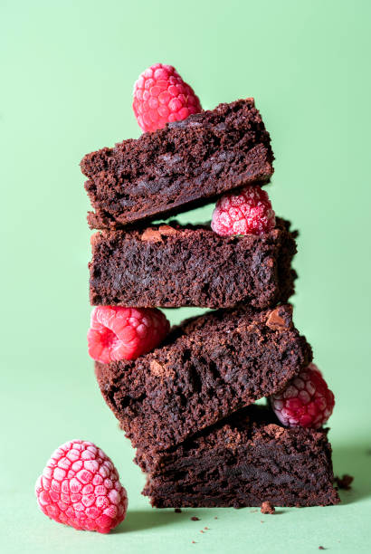 Stack of brownies and frozen raspberries. Dark chocolate dessert Chocolate brownies and raspberries fruits in a stack on a green mint background. Chocolate dessert and frozen berries. Sweet food. Famous dessert. aqua menthe photos stock pictures, royalty-free photos & images
