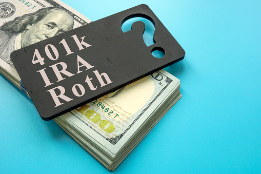 A Stack of cash and plate with words 401k, IRA and Roth retirement plans.