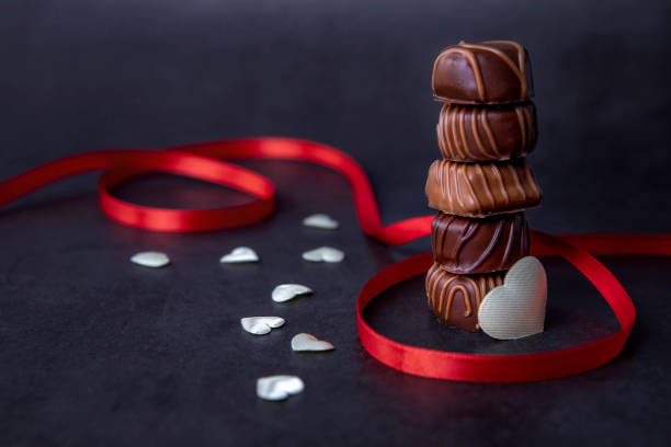 Stack of Chocolate candy and red ribbon on black stock photo