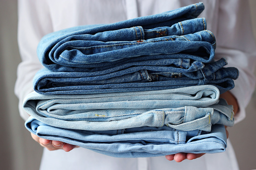 Stack of folded jeans in hands. High quality photo