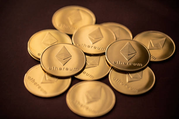 Stack of golden ether coins or Ethereum coins close up depicting cryptocurrency and digital money Stack of golden ether coins or Ethereum coins close up on dark red background depicting cryptocurrency and digital money.  Taken in Jurong, Singapore on  6 May 21.  With Ethereum  stock pictures, royalty-free photos & images