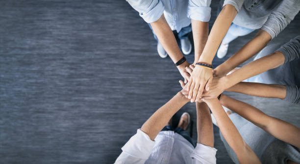 Stack of hands. Unity and teamwork concept. Close up top view of young business people putting their hands together. Stack of hands. Unity and teamwork concept. holding hands stock pictures, royalty-free photos & images