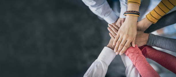Stack of hands. Unity and teamwork concept. Close up top view of young business people putting their hands together. Stack of hands. Unity and teamwork concept. student leader stock pictures, royalty-free photos & images