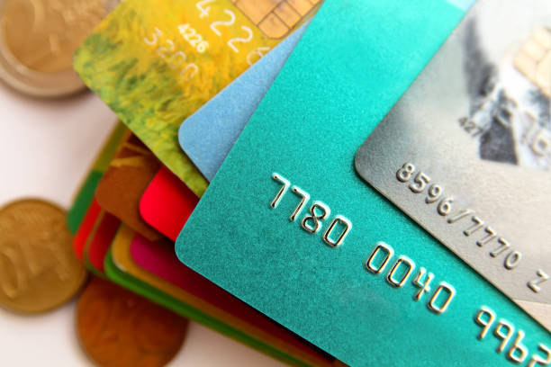 stack of multicolored credit cards and scattered coins, close up stock photo