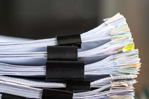 Stack of papers files documents achieves with clips on work in office