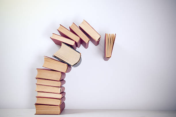 A stack of piled books toppling over stock photo