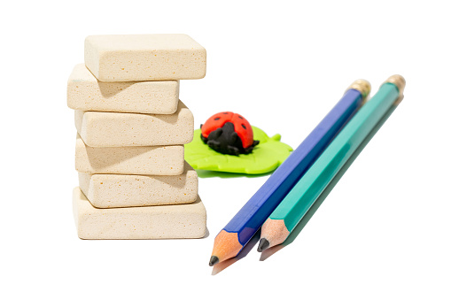 Stack of uniform rectangular stationery erasers, two pencils and eraser for kids on white isolated background