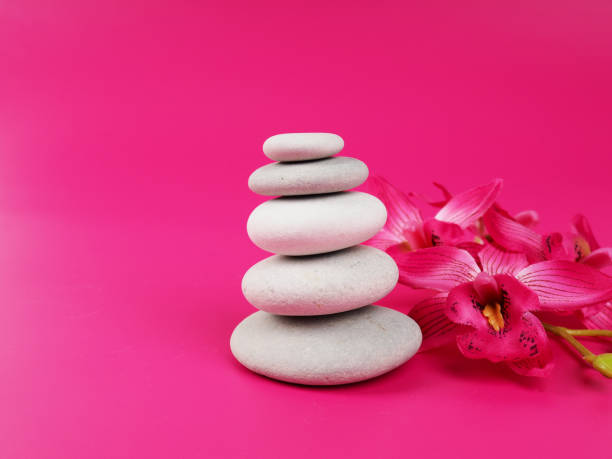 A stack of white zen stones on a pink background, minimalism stock photo