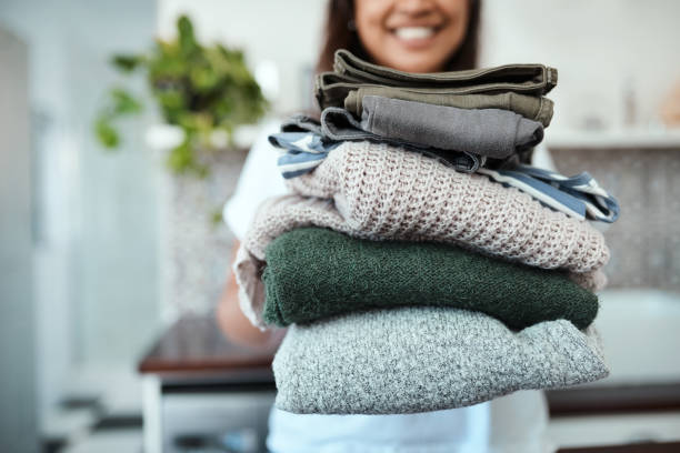 Stacked and ready to be packed Closeup shot of a young woman holding a pile of folded laundry at home washing stock pictures, royalty-free photos & images