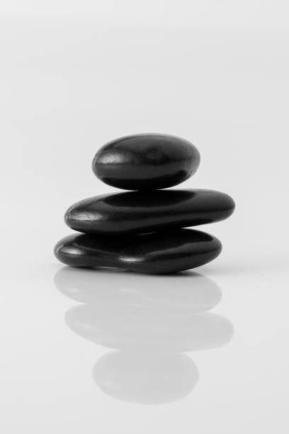 stacked black stones on white background stock photo