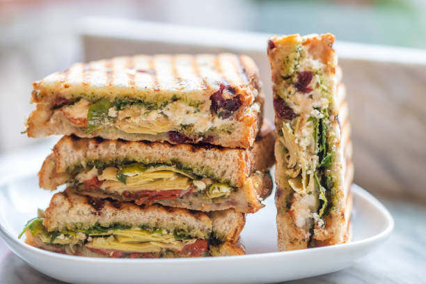 sándwiches vegetarianos apiladas de arúgula, alcachofa, el sol seca de tomate, pesto - sandwich fotografías e imágenes de stock