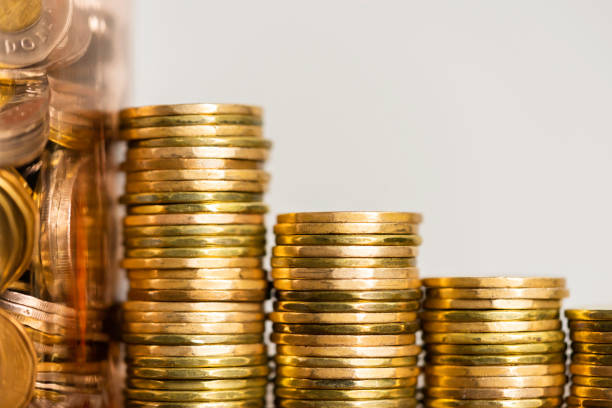 Stacks of Coins next to a jar full of coins stock photo