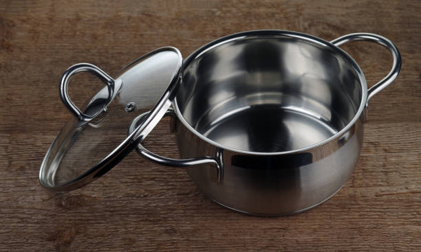 A stainless steel casserole with the lid removed on a rough wooden stock photo