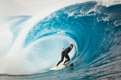 A male surfer cruising along a huge wave.
