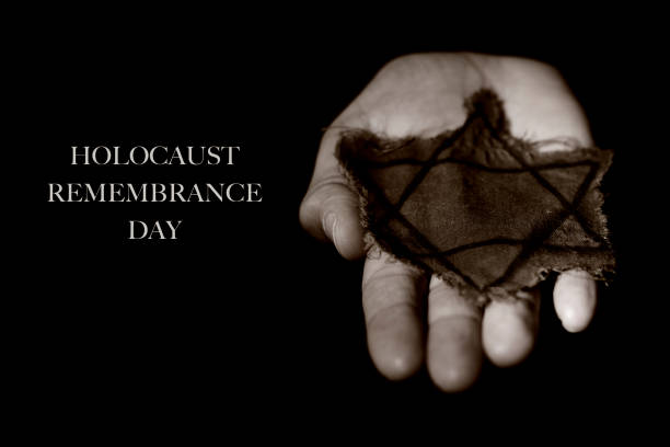 star of david and text holocaust remembrance day closeup of the star of david in an old and ragged badge on the hand of a man, and the text holocaust remembrance day on a black background holocaust remembrance day stock pictures, royalty-free photos & images