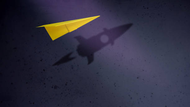 стартап-компания и мотивация в бизнес-концепции. бумажные самолеты, летящие с тенью ракеты над стеной - понятия стоковые фото и изображения
