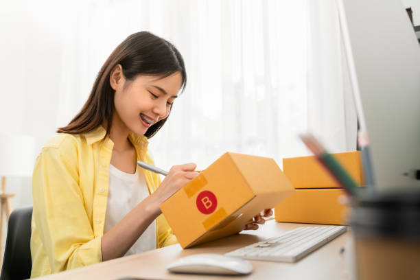 Startup small business concept, young woman owner working and packing on the box to customer at home office, seller prepares the delivery. stock photo