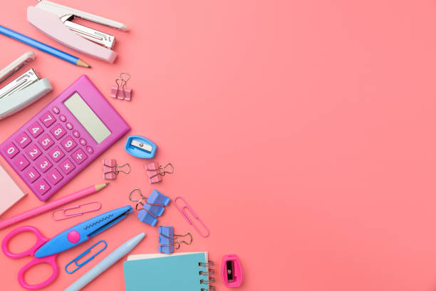 Stationary concept, Flat Lay top view Photo of Scissors, pencils, paper clips,calculator,sticky note,stapler and notepad in pink and blue tone on pink background with copy space. stock photo